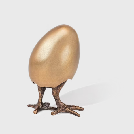 Kyckling i ggskal som r p vg att ta sig ut i vrlden med ftterna frst. Gjuten brons
